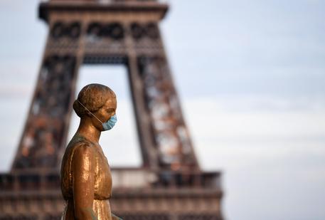 A picture taken on May 2, 2020 shows a bronze statue wearing a face mask emmulating the actions of many citizens to protecting themselves against the novel coronavirus, COVID-19 at the Parvis des Droits de l'Homme, with the Eiffel Tower in background in Paris, on the 47th day of a strict lockdown in France aimed at curbing the spread of the COVID-19 pandemic, caused by the novel coronavirus. (Photo by Alain JOCARD / AFP)