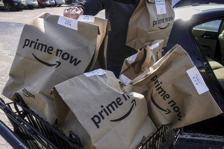 FILE - In this Feb. 8, 2018, file photo, Amazon Prime Now bags full of groceries are loaded for delivery by a part-time worker outside a Whole Foods store in Cincinnati. Amazons Prime Day deals are coming to the aisles of Whole Foods, as the online retailer seeks to lure more people to its Prime membership after recently hiking up the price. (ANSA/AP Photo/John Minchillo, File) [CopyrightNotice: AP]