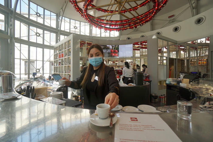 Una giovane commessa serve un caffè al banco, nella caffetteria Illy a San Marco  a Venezia, 18 maggio 2020. ANSA/ANDREA MEROLA