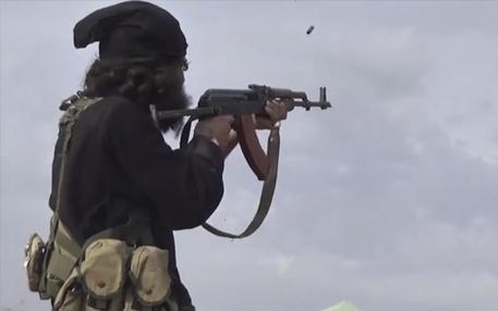 This frame grab from video posted online Monday, March 18, 2019, by the Aamaq News Agency, a media arm of the Islamic State group, shows an IS fighter firing his weapon during clashes with the U.S.-backed Syrian Democratic Forces (SDF) fighters, in Baghouz, the IS group's last pocket of territory in Syria. U.S.-backed Syrian forces fighting the IS announced Tuesday they have taken control over an encampment in an eastern Syrian village where IS militants have been besieged for months, refusing to surrender. (Aamaq News Agency via AP)