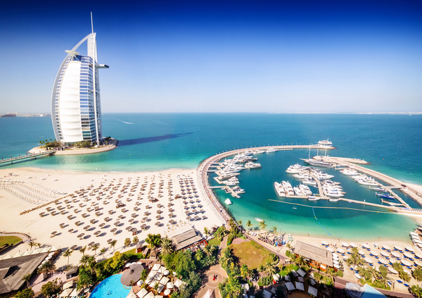 Dubai, United Arab Emirates - December 10, 2014: The Burj Al Arab Hotel, left side on the beach near Madinat Jumeriah Resort. The Burj Al Arab is a luxury hotel located in Dubai, United Arab Emirates. At 321 m (1,053 ft), it is the fourth tallest hotel in the world. The Burj Al Arab stands on an artificial island 280 m (920 ft) out from Jumeirah beach, and is connected to the mainland by a private curving bridge. It is an iconic structure whose shape mimics the sail of a ship.