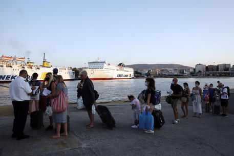 epa08602511 Tourists wearing protective face masks wait with their luggage to embark a ship in the port of Piraeus, Greece, 14 August 2020. Trips to the Greek islands are carried out with all the precautionary measures to fight the spreading of the coronavirus disease (COVID-19).  EPA/ALEXANDROS VLACHOS