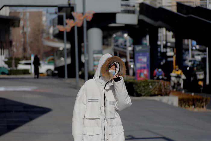 epa08910732 A woman wearing a protective face mask walks in the street in Beijing, China, 30 December 2020, amid the coronavirus disease (COVID-19) pandemic. China reported 24 new cases of COVID-19 on the mainland on 29 December 2020.  EPA/WU HONG