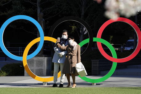 epa08317661 A couple wearing protective face masks takes selfies of an Olympic Rings monument in front of the Japan Olympic Committee headquarters in Tokyo, Japan, 24 March 2020. Later in the day, Japanese prime minister Shinzo Abe is scheduled to hold phone talks with International Olympic Committee (IOC) president Thomas Bach of Germany regarding the possible postponement of the Tokyo 2020 Olympic Games due to the coronavirus COVID19 pandemic.  EPA/FRANCK ROBICHON