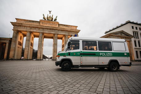 epa08307840 A police car passes-by the Brandenburg Gate in Berlin, Germany, 19 March 2020. In Berlin, shops, museums and concert halls are closed. Many people switched to home office in order to prevent the spread of the coronavirus SARS-CoV-2 which causes the Covid-19 disease.  EPA/CLEMENS BILAN