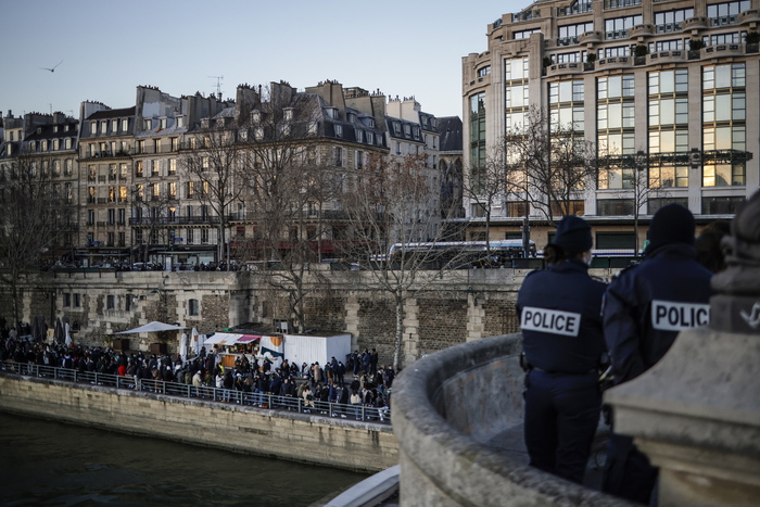 epa08930641 French Police officers stand as hundreds of people gather and enjoy a take away beer on the Seine river banks in Paris, France, 10 January 2021. French authorities stay on alert in a bid to contain the highly contagious UK variant of COVID-19 that appears in France over the past weeks.  EPA/YOAN VALAT