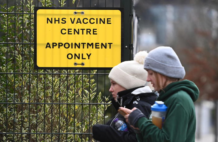 epa09001294 People walk past a sign to a Covid-19 vaccination centre in London, Britain, 10 February 2021. British Vaccines Minister Nadhim Zahawi has stated he was confident the NHS would be able to reach the target of immunising all those over the age of fifty by May. Some twelve million people across the UK have already received their first dose of a Covid-19 vaccine.  EPA/ANDY RAIN