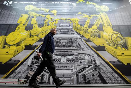 In a file photo a man walks along a poster that shows robots in a car factory at the Hannover Industry Fair (Hannover Messe) in Hanover, Germany, 31 March 2019. EPA/JENS SCHLUETER