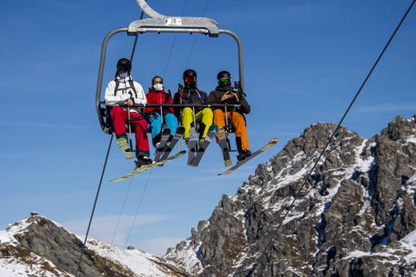 epa08785743 Skiers wearing face masks ride a chairlift on the opening day of the Verbier ski area in the Swiss Alps during the coronavirus disease (COVID-19) outbreak, in Verbier, Switzerland, 30 October 2020.  EPA/JEAN-CHRISTOPHE BOTT