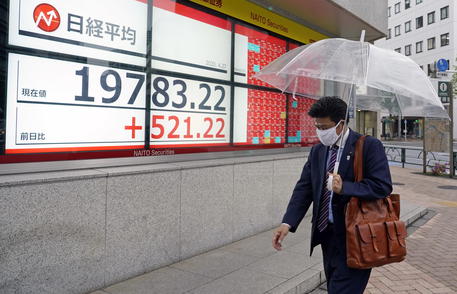 epa08385907 A pedestrian wearing a face mask walks before a stock market indicator board in Tokyo, Japan, 27 April 2020. Tokyo stocks rose sharply after the Bank of Japan decided new stimulus measures to counter the impact on the economy of the coronavirus pandemic. The 225-issue Nikkei Stock Average gained 521.22 points, or 2.71 percent, to close at 19,783.22.  EPA/FRANCK ROBICHON