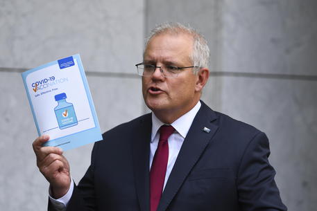 epa08985929 Australian Prime Minister Scott Morrison holds up a COVID-19 vaccination leaflet as he speaks to the media during a press conference at Parliament House in Canberra, Australia, 04 February 2021. Morrison announced the Australian government has secured 10 million more doses of the Pfizer/BioNTech vaccine against COVID-19.  EPA/LUKAS COCH AUSTRALIA AND NEW ZEALAND OUT