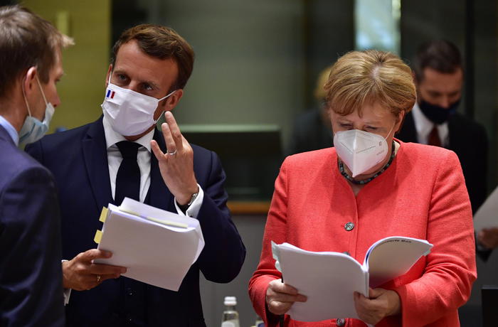 epa08557286 German Chancellor Angela Merkel (R) chats with French President Emmanuel Macron (C) while both wear face masks during a roundtable discussion on the fourth day of the ongoing Special European Council leaders' summit, the first face-to-face meeting between EU statespeople held since the eruption of the ongoing pandemic of the COVID-19 disease caused by the SARS-CoV-2 coronavirus, in Brussels, Belgium, 20 July 2020. The heads of state and government discussed the bloc's response to the pandemic and the new long-term budget.  EPA/JOHN THYS / POOL