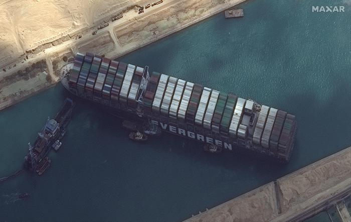 epa09099441 A handout satellite image made available by MAXAR Technologies shows multiple tug boats positioned alongside the 'Ever Given' and dredging operations in progress, in the Suez Canal, Egypt, 26 March 2021. The large container ship Ever Given ran aground in the Suez Canal on 23 March, blocking passage of other ships and causing a traffic jam for cargo vessels. The head of the Suez Canal Authority announced on 25 March that 'the navigation through the Suez Canal is temporarily suspended' until the floatation of the Ever Given is completed. Its floatation is being carried out by eight large tugboats that are towing and pushing the grounding vessel.  EPA/MAXAR TECHNOLOGIES HANDOUT -- MANDATORY CREDIT: SATELLITE IMAGE 2020 MAXAR TECHNOLOGIES -- the watermark may not be removed/cropped -- HANDOUT EDITORIAL USE ONLY/NO SALES