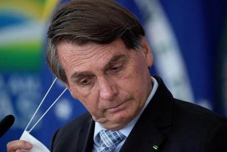 epa09066297 Brazilian President Jair Bolsonaro removes his mask during the signing ceremony of bills to expand the capacity to purchase vaccines by the Federal Government, at the Planalto Palace, in Brasilia, Brazil, 10 March 2020.  EPA/Joedson Alves