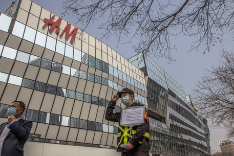 epa09095384 A security officer holds a sign reading 'no photos for commercial use' in front of an H&M store in a shopping area of Sanlitun in Beijing, China, 25 March 2021. International clothing brands H&M, Nike and Adidas face backlash in China for refusing to buy Xinjiang cotton over claims of forced labor and genocide in the region.  EPA/ROMAN PILIPEY