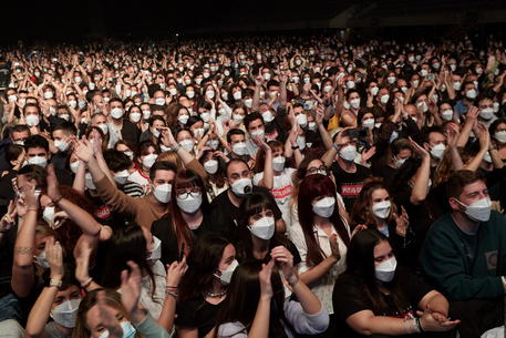 epa09101859 Members of the audience react as Spanish band Love of Lesbian performs on stage in front of 5,000 people at the Palau Sant Jordi arena in Barcelona, Catalonia, Spain, 27 March 2021. This is the first crowded concert in Spain since the beginning of the COVID-19 coronavirus pandemic a year ago. People had to go through a PCR test and were given FPP2 masks before entering the test concert venue.  EPA/Alejandro Garcia
