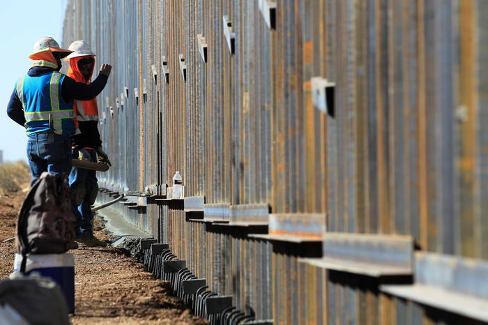 epa08858443 Workers from the Ultimate Concrete construction company speed up their task to finish the metal wall ordered by US President Donald J. Trump, on the border with Columbus County, New Mexico (USA), in the town of Puerto Palomas, Chihuahua State, Mexico, 02 December 2020. Construction companies are accelerating the works of the border wall before Joe Biden takes office in January.  EPA/LUIS TORRES