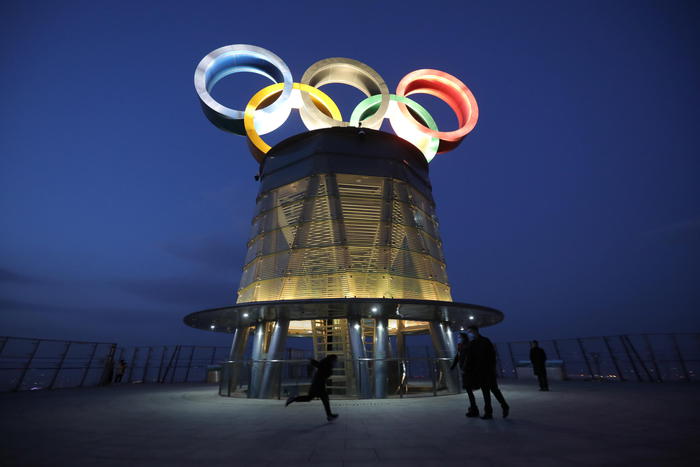 epaselect epa08988852 Visitors walk near the lit-up Olympic rings atop of the Olympic Tower in Beijing, China, 05 February 2021. The 2022 Beijing Winter Olympics are scheduled to take place from 04 to 20 February 2022.  EPA/WU HONG