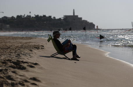epa08688494 An Israeli woman reads a book at the beach during the lockdown in Tel Aviv, Israel, 22 September 2020.  Israeli police began to enforce a three week lockdown during the Jewish holidays aimed to prevent the spread of the coronavirus.  EPA/ATEF SAFADI