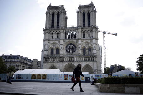 epa09134858 A woman walks by Notre-Dame cathedral on the eve of the second anniversary of the cathedral's fire in Paris, France, 14 April 2021. Two years ago, on 15 April 2019, the 850-year-old Notre-Dame Cathedral of Paris suffered a devastating fire. Some 500 firefighters managed to prevent the entire cathedral from being reduced to ashes, although its celebrated spire has been destroyed.  EPA/YOAN VALAT