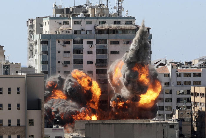 A ball of fire erupts from the Jala Tower as it is destroyed in an Israeli airstrike in Gaza city controlled by the Palestinian Hamas movement, on May 15, 2021. - Israeli air strikes pounded the Gaza Strip, killing 10 members of an extended family and demolishing a key media building, while Palestinian militants launched rockets in return amid violence in the West Bank. Israel's air force targeted the 13-floor Jala Tower housing Qatar-based Al-Jazeera television and the Associated Press news agency. (Photo by Mahmud hams / AFP)