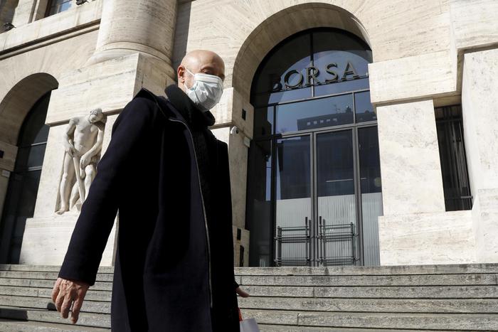 Persone con mascherine per proteggersi dal Coronavirus in piazza affari davanti all'ingresso della Borsa a Milano, 24 gennaio 2020.ANSA/Mourad Balti Touati