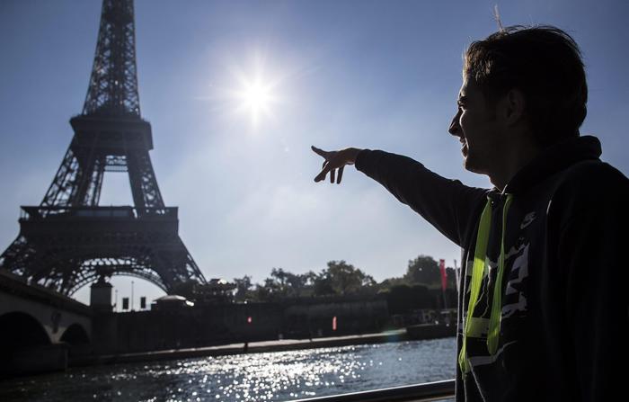 epa04971833 Syrian refugee and former law student from Damascus, Omar, 20, points at the Eiffel Tower as he takes a guided boat tour down the river Seine as part of a day-trip in central Paris organized by French NGO 'Secours Populaire', in Paris, France, 10 October 2015. Several hundred Syrian and Iraqi refugees arriving from Munich in Germany had been granted asylum in France and settled in a leisure-park facility in Cergy outside Paris, earlier in September 2015.  EPA/IAN LANGSDON