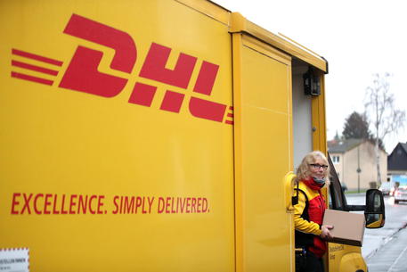epa08885599 A parcel carrier of the Deutsche Post DHL Group logistics and postal services company delivers parcels in a residential area in Dortmund, Germany, 15 December 2020. According to a company spokesman, Deutsche Post DHL Group expects to break the record of 11 million parcel shipments per day several times in the run-up to Christmas.  EPA/FRIEDEMANN VOGEL