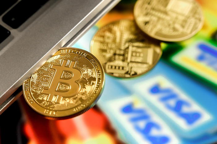 epa09018335 A bitcoin in a slot-in drive reflects in front of a monitor showing credit cards, in Duesseldorf, Germany, 17 February 2021. For the first time, the cryptocurrency Bitcoin has exceeded the mark of 50,000 dollars. Most recently, it became known that Elon Musk, CEO of the US electric car manufacturer Tesla, is said to have invested 1.5 billion dollars in Bitcoin. In recent weeks, he had boosted Bitcoin as well as other Internet currencies with positive news via the short message service Twitter. Credit card provider MasterCard also announced that it would open its payment network to cryptocurrencies. Visa plans to help banks introduce trading with Bitcoin and other cryptocurrencies by launching software with API access.  EPA/SASCHA STEINBACH