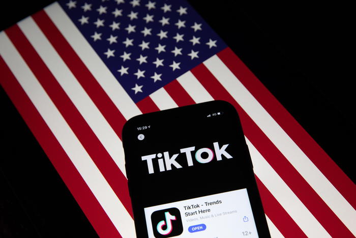 epa08685861 A generic illustration shows the icon of Chinese internet media app TikTok on a phone, and the US flag on a laptop screen, in Beijing, China, 21 September 2020. Chinese-owned mobile app WeChat was set to stop operation in the U.S. on midnight 20 September 2020.  EPA/ROMAN PILIPEY