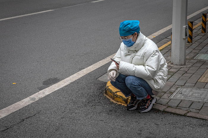 epa08331687 A woman wearing a protective face mask asits next to a road, in Wuhan, China, 30 March 2020. Wuhan, the epicenter of the coronavirus outbreak, partly lifted the lockdown allowing people to enter the city after more than two months. Chinese authorities eased the quarantine measures as cases of Covid-19 across China have plummeted, ac  EPA/ROMAN PILIPEY