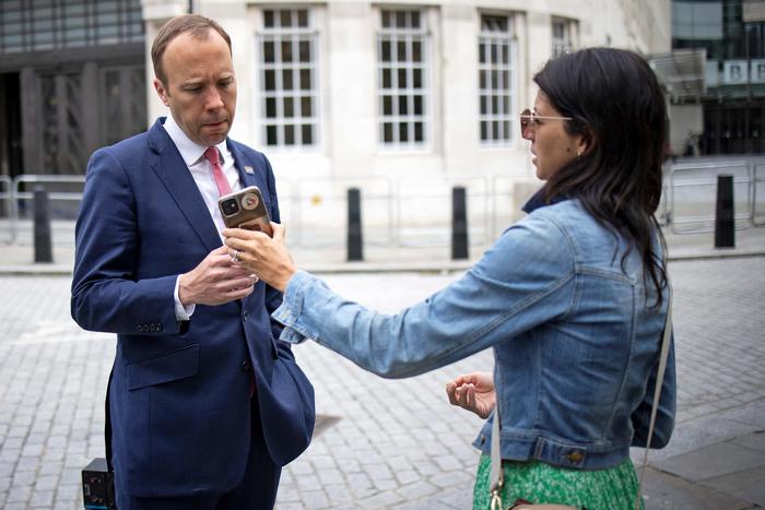 Britain's Health Secretary Matt Hancock (L), looks at the phone of his aide Gina Coladangelo as they leave the BBC in central London on June 6, 2021, after appearing on the BBC political programme The Andrew Marr Show. - A British newspaper reported on June 25, 2021, that Britain's Health Secretary Matt Hancock has been having an affair with a close aide Gina Coladangelo, whom he appointed to his team in secret last year. (Photo by Tolga Akmen / AFP)
