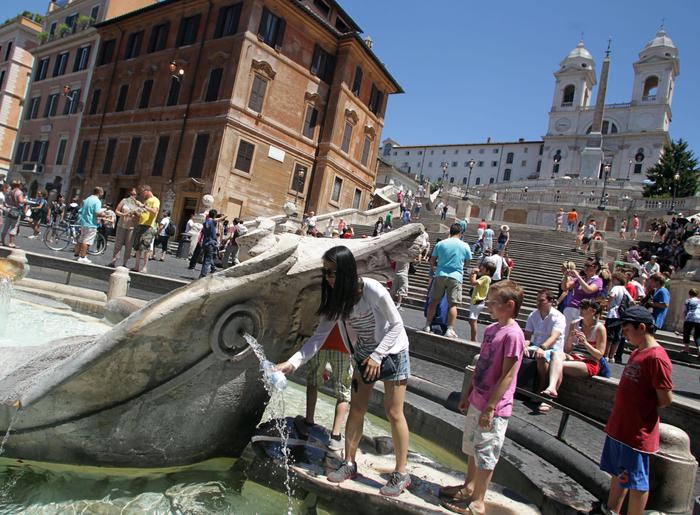 Alcuni turisti si rinfrescano con l'acqua delle fontane di Piazza di Spagna per difendersi dall'ondata di caldo a Roma. E' previsto un allarme meteo per alta temperatura. Roma 23 giugno 2012 ANSA/FABIO CAMPANA