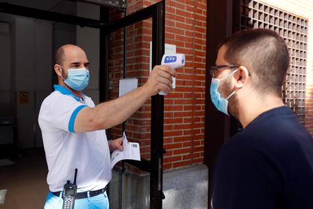 epa08612279 A health worker takes the temperature of a man that arrives to the Health Center Los Angeles to undergo a PCR coronavirus test in Villaverde district in Madrid, Spain, 19 August 2020. Madrid's regional Government is running random PCR tests around all districts in the capital city in an attempt to detect coronavirus asymptomatic patients between ages 15 and 49, as the average age of infected patients has reasonably gone down.  EPA/MARISCAL