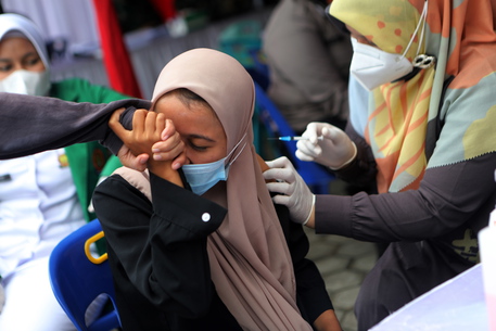 epa09345419 A woman receives a dose of Sinovac vaccine during a mass vaccination for locals in Banda Aceh, Indonesia, 15 July 2021. Indonesia is speeding its vaccination program as the number of COVID-19 cases reach over 2,600,000 since the beginning of the pandemic.  EPA/HOTLI SIMANJUNTAK