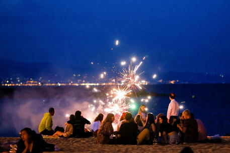 epa09297952 Several young people talk as they mark St. John's night (La Noche de San Juan) on Barceloneta beach, in Barcelona, northeastern Spain, late 23 June 2021 (issued 24 June 2021). Traditionally, bonfires are lit in Spanish beaches on the previous night to St. John's Day to mark the festivity, although local authorities in some Spanish coastal cities decided to close their beaches to avoid gatherings to prevent a possible spreading of the COVID-19 coronavirus disease.  EPA/QUIQUE GARCIA