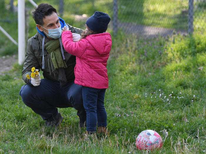 A father, wearing a health mask, plays with his daughter in a small park near his home in San Donato Milanese, near Milan, Italy, 1 April  2020. The circular issued yesterday by the Interior Ministry that allows only parents to walk with their minor children near their home has been fiercely criticized. f Piazza del Campo Square in Siena, Italy, 01 April 2020. Italy is under lockdown in an attempt to stop the widespread of the SARS-CoV-2 coronavirus causing the Covid-19 disease. ANSA/DANIEL DAL ZENNARO