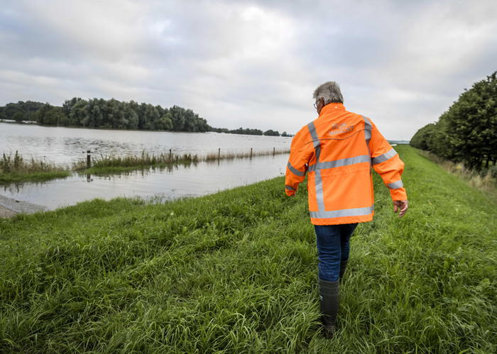 epa09349772 A woman from the voluntary dike guard checks the dam in evacuated Arcen, North Limburg, The Netherlands, 17 July 2021.  Heavy rainfall has led to floods and damages in various parts of the Netherlands and western Europe.  EPA/REMKO DE WAAL