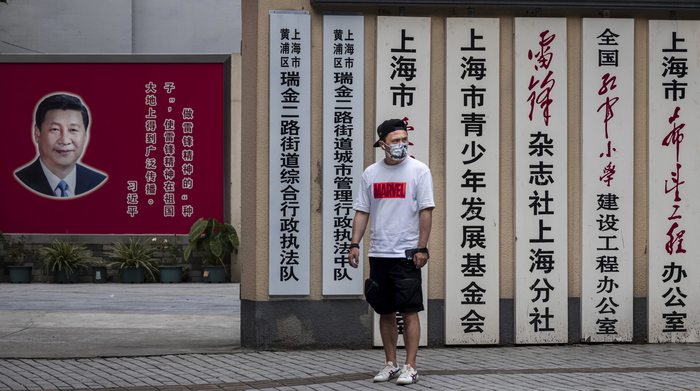 epa09418673 A man wearing a mask for protection walks on the street in front of the local Communist Party headquarters with poster of Chinese President Xi Jinping in Shanghai, China, 18 August 2021.  EPA/ALEX PLAVEVSKI
