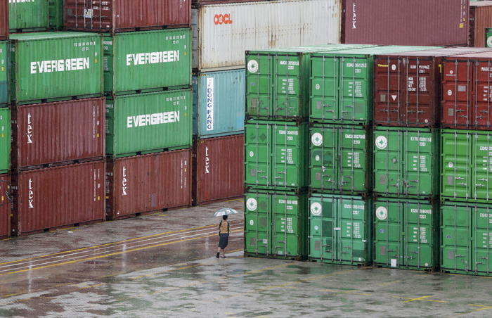 epa09400692 A man walks pass among the containers piled up at Asia World Port Terminal in Yangon, Myanmar, 06 August 2021. According to the report of World Bank's Myanmar Economic Monitor, Myanmar's economy is expected to contract around 18 percent in 2021 fiscal year (October 2020-September 2021) due to ongoing political turmoil and a rapidly rising third-wave of COVID-19 cases. The share of Myanmar's population living in poverty is likely to more than double by the beginning of 2022, compared to 2019 levels.  EPA/STRINGER