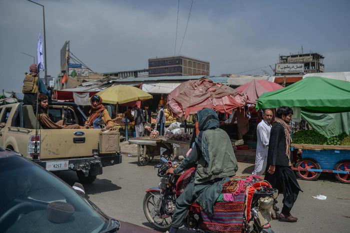 Taliban fighters on a pick-up truck (L) move around a market area, flocked with local Afghan people at the Kote Sangi area of Kabul on August 17, 2021, after Taliban seized control of the capital following the collapse of the Afghan government. (Photo by Hoshang Hashimi / AFP)