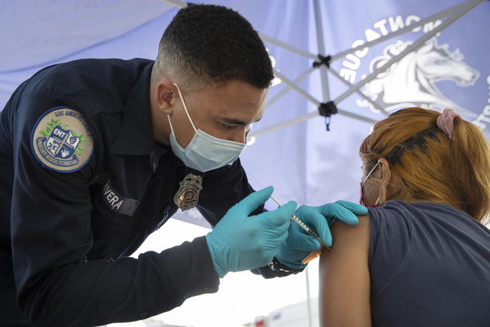 epa09426889 Los Angeles County Energy Medical Technician Brandon Rivera (L) administers a shot of the Pfizer-BioNTech Covid-19 vaccine at a pop-up COVID-19 vaccination clinic at the Montague Charter Academy of Arts and Sciences in Arleta, California, USA, 23 August 2021. The Food and Drug Administration on Monday granted full approval to Pfizer and BioNTech's Covid-19 vaccine, making it the first FDA approved Covid-19 vaccine in the nation.  EPA/CAROLINE BREHMAN