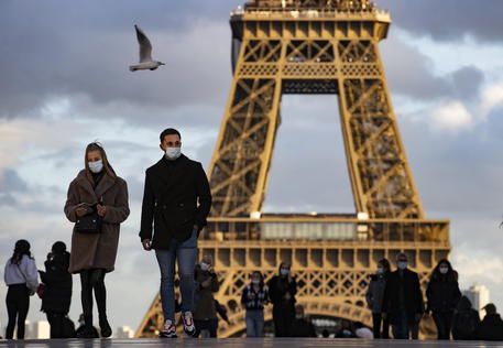 epa08775725 People wearing protective face masks walk near the Eiffel Tower, in Paris, France, 26 October 2020. France is in the midst of a second wave of the COVID-19 coronavirus pandemic, recording a new high of 50,000 daily new cases - although Jean-Francois Delfraissy of France's Scientific Council estimates that bew Covid cases are rising by a rate closer to 100,000 per day. France has currently placed 45 million of its citizen across several 'departments' (counties) under a night-time curfew prohibiting leaving one's house between 9pm and 6am. French President Emmanuel Macron is convening  a defense council on 27 October to draft new measures to battle the rise in Covid-19 cases.  EPA/IAN LANGSDON