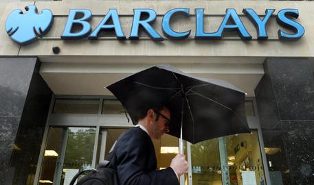 epa04196260 A pedestrian shelters from the rain as he passes a Barclays bank branch in London, Britain, 08 May 2014. Britain's Barclay's bank on 08 May said it would cut 14,000 jobs this year as part of a strategy review, an increase from the 12,000 jobs it had previously indicated.  EPA/ANDY RAIN