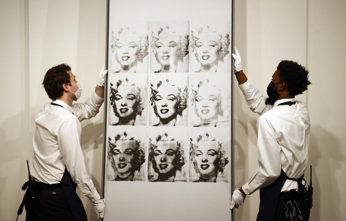 epa09566454 Sotheby's employees hold US artist Andy Warhol's 'Nine Marilyns, 1962', on display at Sotheby's auction house during a press preview for the upcoming Marquee Evening Sales auctions in New York, New York, USA, 05 November 2021. The work, part of The Macklowe Collection, is estimated between USD 40-60 million dollars.  EPA/JASON SZENES