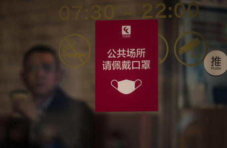 epa09597326 A man seats in a restaurant behind the sign for wearing masks on the doors in Shanghai, China, 22 November 2021.  EPA/ALEX PLAVEVSKI