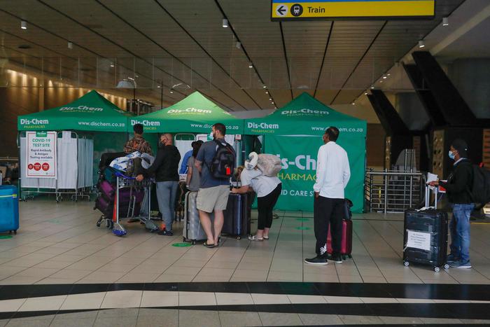 Travellers queue at an area for polymerase chain reaction (PCR) Covid-19 tests at OR Tambo International Airport in Johannesburg on November 27, 2021, after several countries banned flights from South Africa following the discovery of a new Covid-19 variant Omicron. - A flurry of countries around the world have banned ban flights from southern Africa following the discovery of the variant, including the United States, Canada, Australia,Thailand, Brazil and several European countries. The main countries targeted by the shutdown include South Africa, Botswana, eSwatini (Swaziland), Lesotho, Namibia, Zambia, Mozambique, Malawi and Zimbabwe. (Photo by Phill Magakoe / AFP)