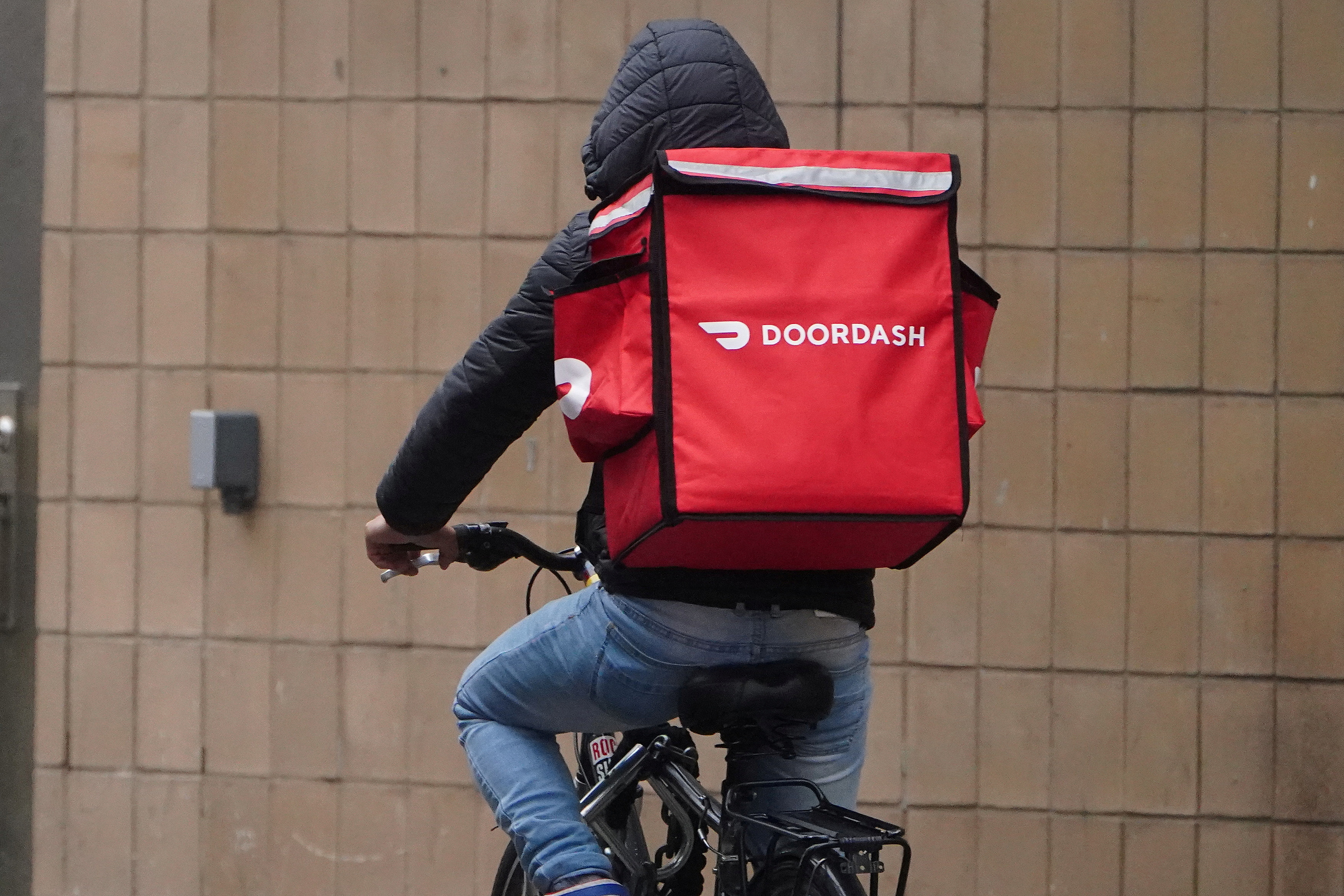 FILE PHOTO: A delivery person for Doordash rides his bike in the rain during the coronavirus disease (COVID-19) pandemic in the Manhattan borough of New York City, New York, U.S., November 13, 2020. REUTERS/Carlo Allegri/File Photo