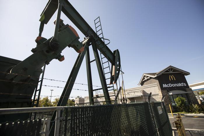 epa07874206 A pump jack is in action next to a McDonald's in the Signal Hill's commercial area in Los Angeles, California, 23 August 2019. (issued 27 September 2019) With nearly 6,000 active oil and gas wells in the county, according to a Natural Resources Defense Council, Los Angeles remains the largest urban oil field in the US. Of the 18 million people leaving in greater Los Angeles, 600,000 live less than 400 meters from an active well.  The story of the city is deeply intertwined with the oil industry. Old documents show Venice Beach covered with rigs and people walking the streets wearing gasmasks because the air pollution was so intense. This situation led to California being able to edict its own gas emission standards, stricter than those in the rest of the country, to counter the disastrous impact of the combined effects of oil production and traffic. This status was recently revoked by President Trump, a decision that is currently being challenged by the state of California.  EPA/ETIENNE LAURENT