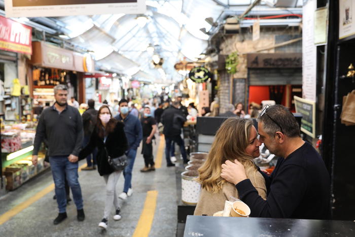 epa09081428 An Israeli couple kissing in the crowded Mahane Yehuda market in Jerusalem, 18 March 2021. Israel returns to an almost normail daily life routine after the removal of government restrictions as Israel vaccinated the majority of the population.  EPA/ABIR SULTAN